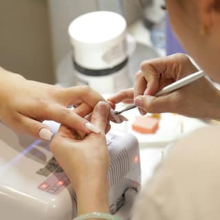 A nail technician shaping a client’s nails at the desk