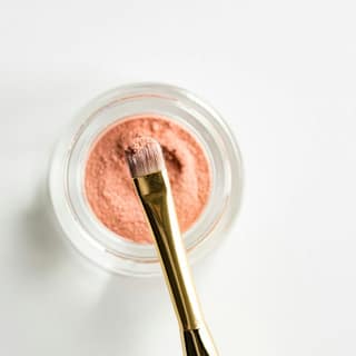 A jar of mask and a brush on a clean worktop